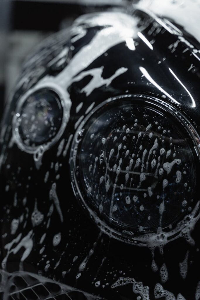 A Close-Up Shot of the Headlight of a Car while being Washed
